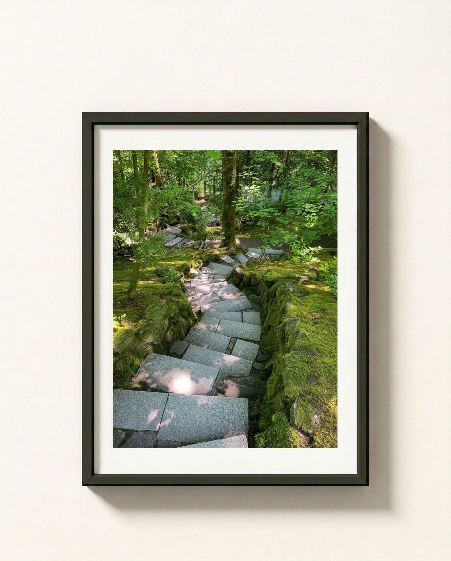 A framed art print depicting a stone path winding through a lush green forest, presented in a black frame with a white mat against a light beige wall.
